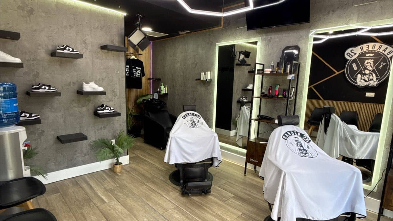 Inside the Granada city centre shop: two chairs with the shop's capes facing the mirrors, trainers displayed on the wall
